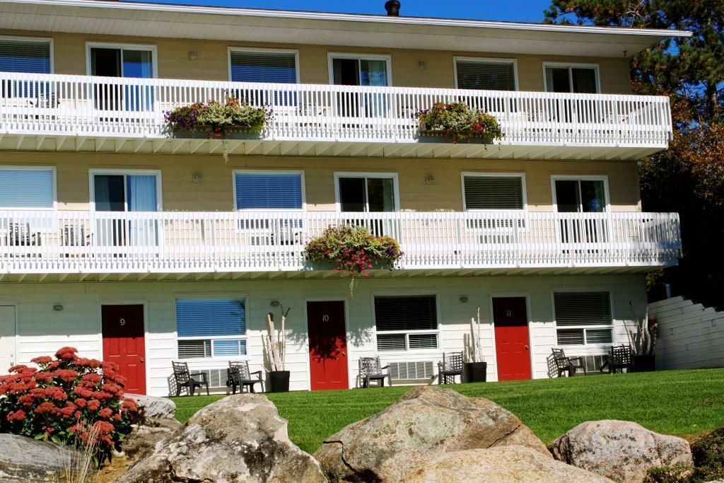 A multi-story building with balconies, a red door, and outdoor seating.