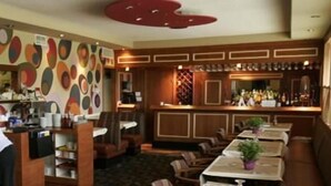 A restaurant with a colorful abstract wall design, wooden furniture, and a bar area. - Wainfleet Motel & Restaurant (Wainfleet)