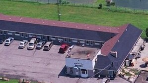 An aerial view of a motel with a parking lot, a swimming pool, and a fenced area. - Wainfleet Motel & Restaurant (Wainfleet)
