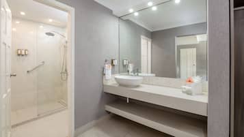A modern bathroom with a glass-enclosed shower, a large mirror, and a white sink.