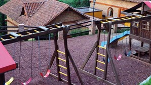 Un parque infantil con columpios y un tobogán, rodeado de edificios de ladrillo con tejados de tejas.