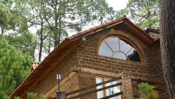 Un edificio rústico de piedra con un gran ventanal de arco y techo de madera.