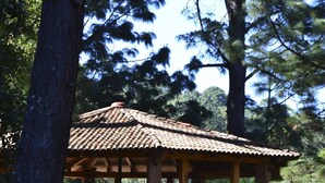 Un pabellón de madera con techo de tejas, rodeado de árboles.