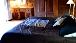 Un dormitorio con pared de ladrillo, armario de madera y cama con colcha.