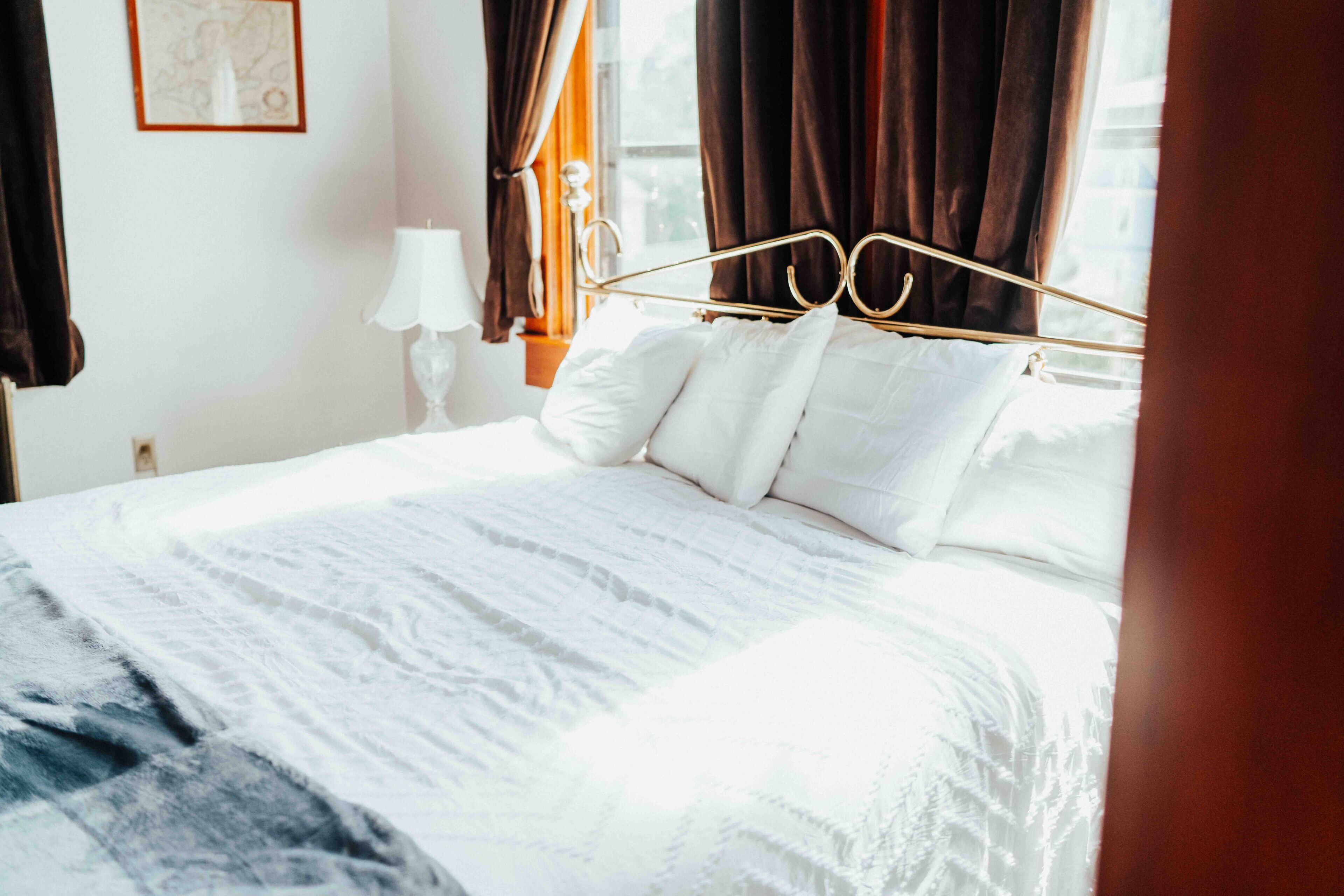 A neatly made bed with white linens and a gold headboard in a hotel room.