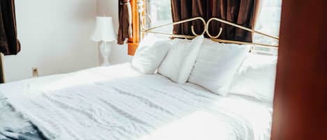 A neatly made bed with white linens and a gold headboard in a hotel room.