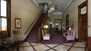 A hotel lobby with a staircase, seating area, and a sign indicating the Mayor's Office. - Town Hall Inn (Lead)