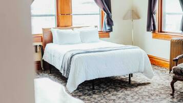 Quarto com cama, mesa de cabeceira, abajur e uma cadeira.