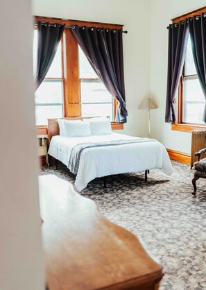 A bedroom with a bed, a nightstand, a lamp, and a chair.