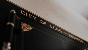 A book titled "CITY OF LEAD - ENGINEER" with a pen resting on it. - Town Hall Inn (Lead)