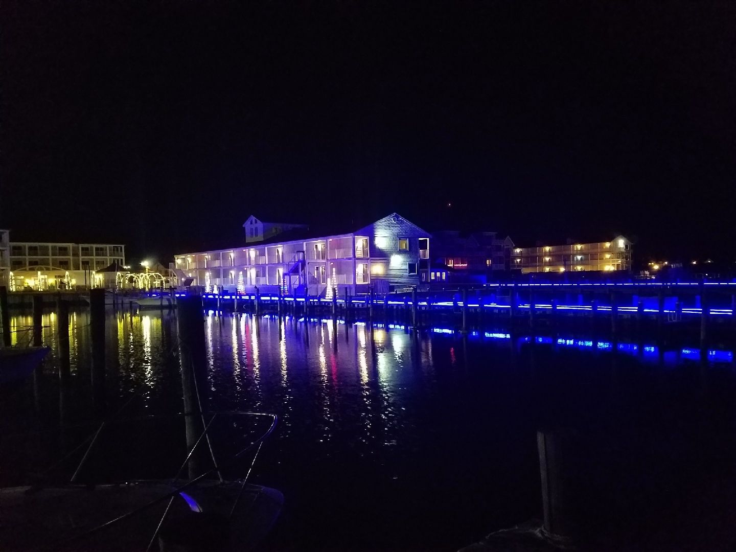 Un hôtel situé au bord de l’eau, avec des lumières bleues qui illuminent le quai et se reflètent sur l’eau.