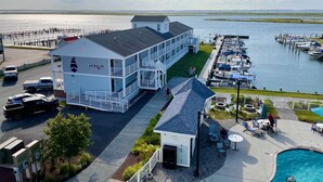 A waterfront hotel with a pool, outdoor seating, and a dock with boats. - Anchor Inn (Chincoteague)