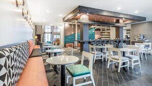 A modern restaurant with a mix of seating options including booths and tables, a bar area, and a visible staircase leading to an upper level. - Anchor Inn (Chincoteague)