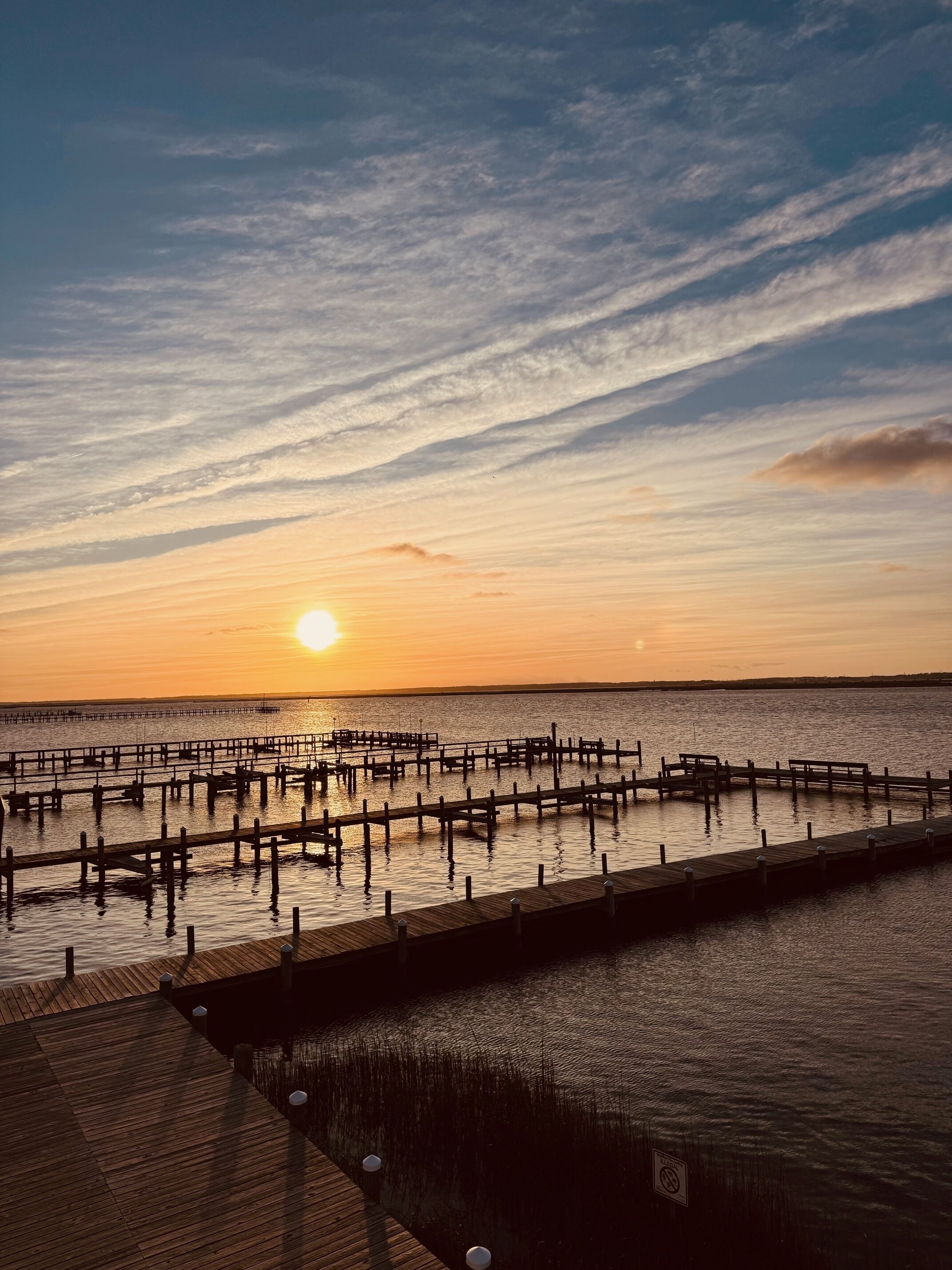 A pier extending into calm water during sunset.