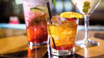 Trois cocktails sur le comptoir en bois d’un bar.
