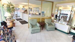A lobby with two armchairs, a reception desk, a large mirror, a potted plant, and a 'BEACH' sign. - Quebec Motel (Wildwood)