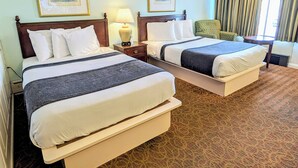 A hotel room with two beds, a nightstand with a lamp, a chair, and a window with curtains. - Quebec Motel (Wildwood)