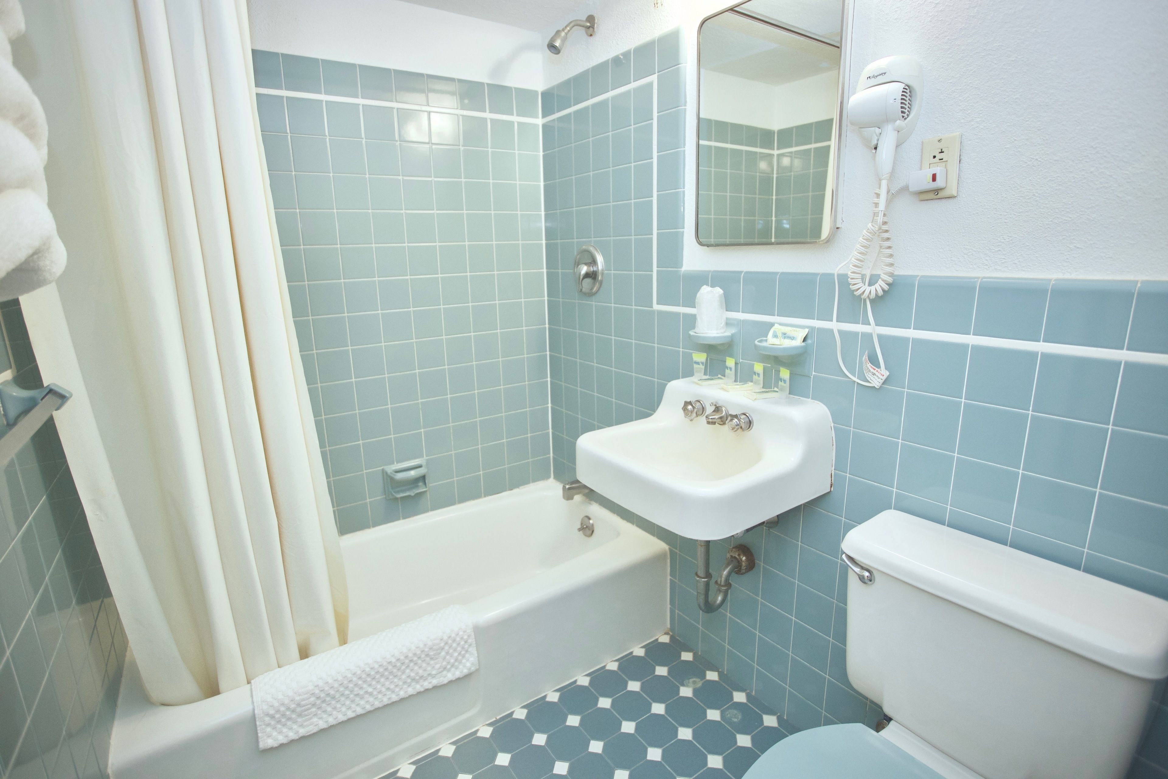 Ein Badezimmer mit Badewanne, Toilette, Waschbecken und einem an der Wand montierten Föhn.