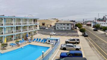 Un hotel con piscina, varios balcones y vista a la calle.