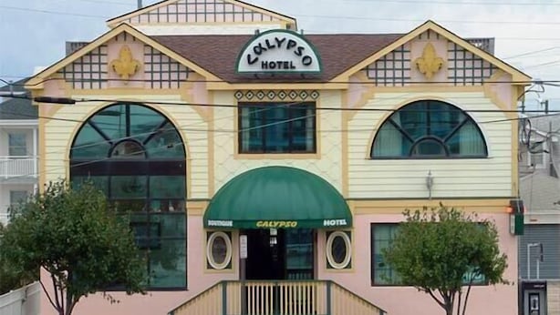 A hotel with a distinctive yellow facade, a green awning, and a sign reading "Calypso Hotel".