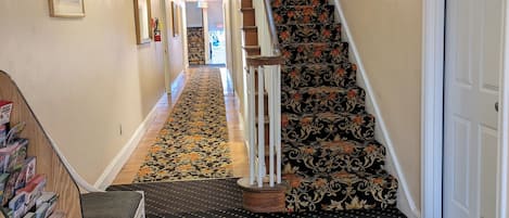 A hallway with a patterned carpet, a staircase with floral upholstery, and a door marked 501.