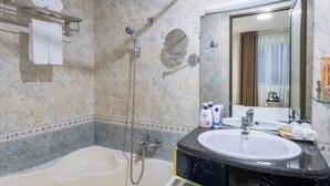 A bathroom with a bathtub, a sink, a shower, and a mirror.