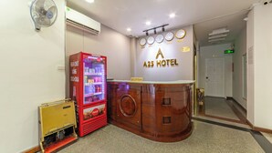 A reception area with a Coca-Cola vending machine, a clock, and a reception desk at A25 Hotel.