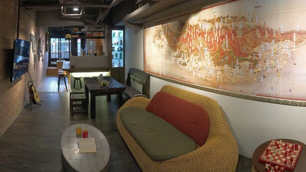 Ein gemütliches Interieur mit einer großen Karte, einem Korbssesselsofa, einer Essecke und einer Bar.