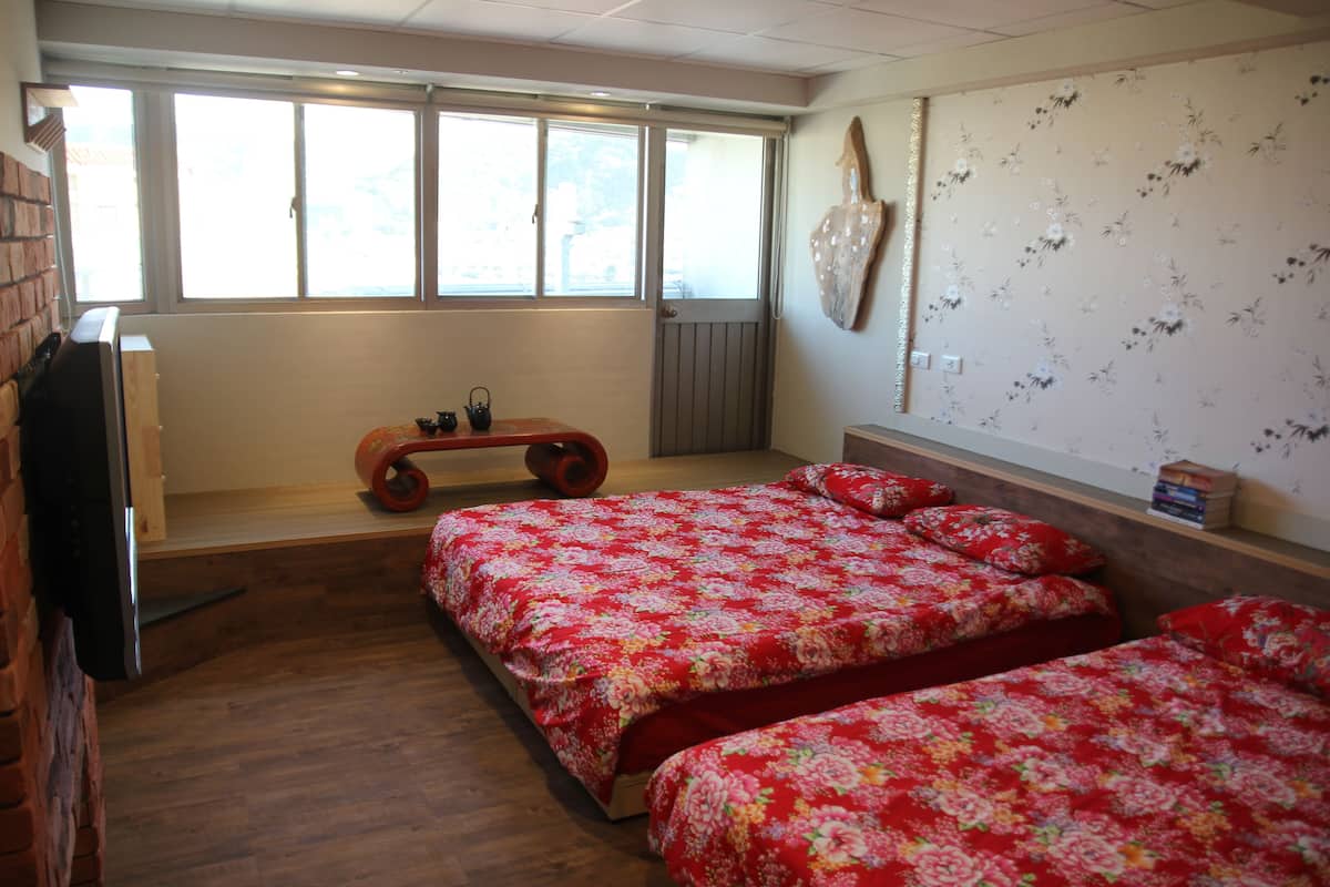 A room with two beds, a wooden bench, a radiator, and a window with blinds.
