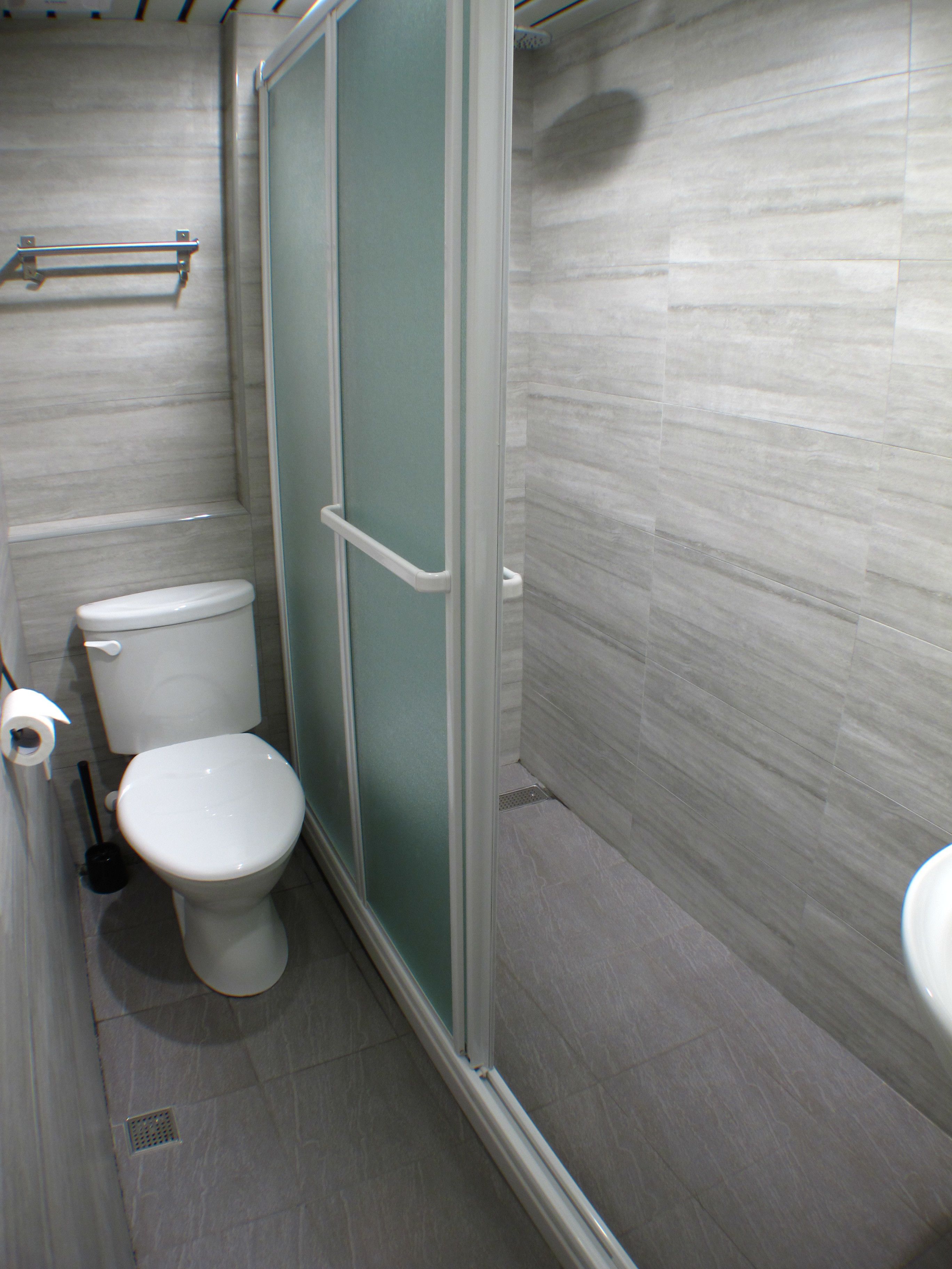Un baño con inodoro, cabina de ducha y lavabo.