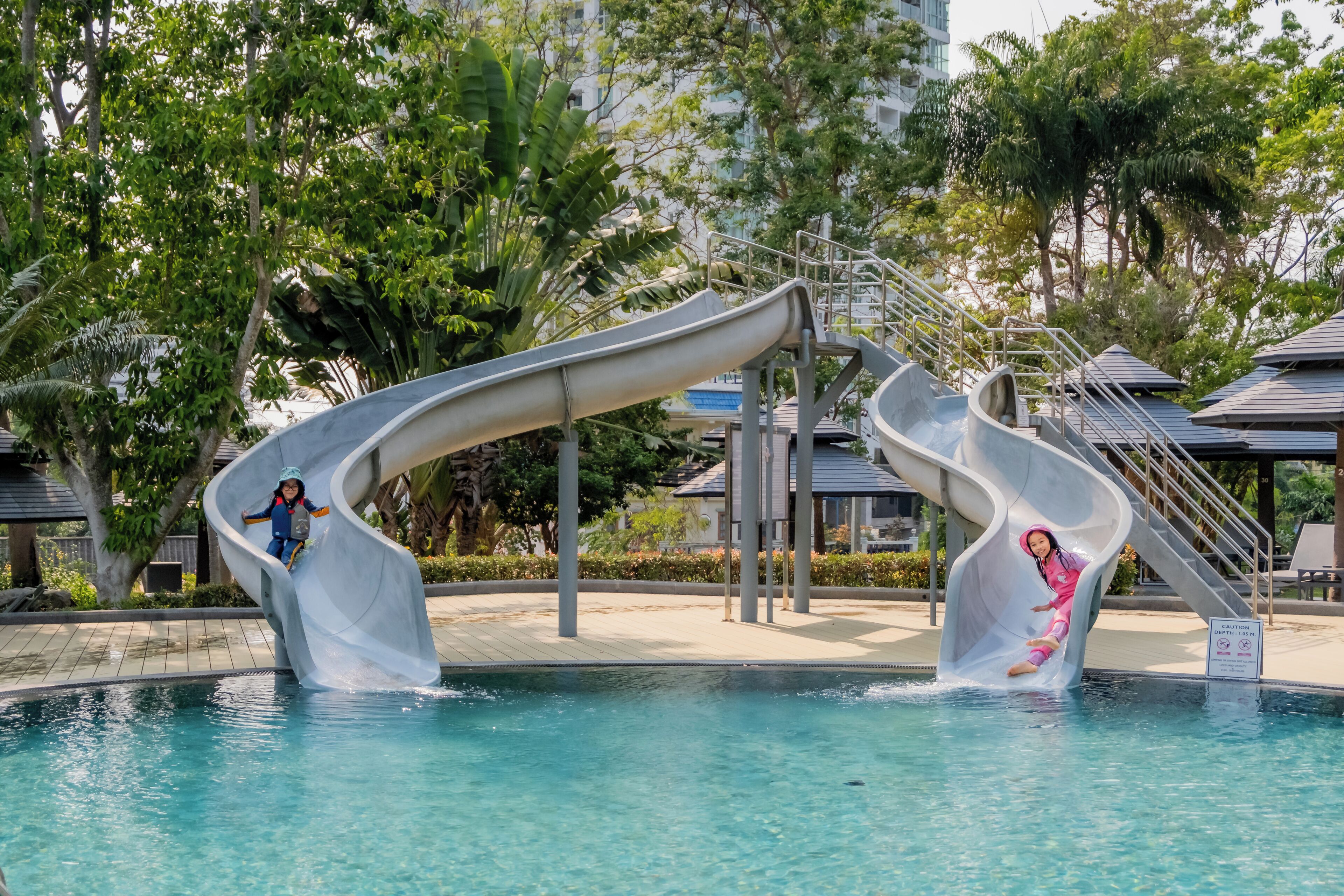 A pool area with two slides and a caution sign.