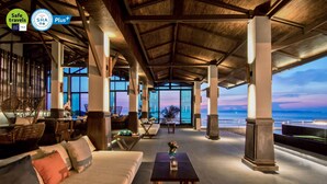 A spacious lounge area with a high ceiling, large windows, and a view of the ocean. - Royal Cliff Beach Terrace Hotel Pattaya (Pattaya)