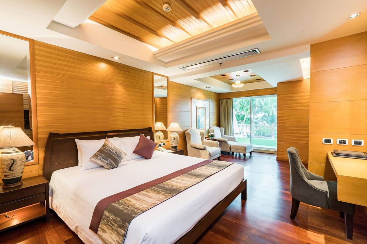 Une chambre d’hôtel avec un grand lit, un bureau, deux chaises et une vue sur l’extérieur.