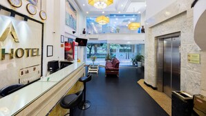 A hotel lobby with a reception desk, seating area, and an elevator.