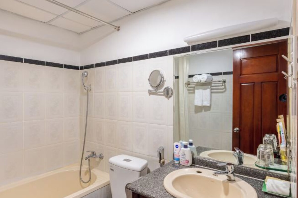 A bathroom with a bathtub, a sink, a mirror, and toiletries.