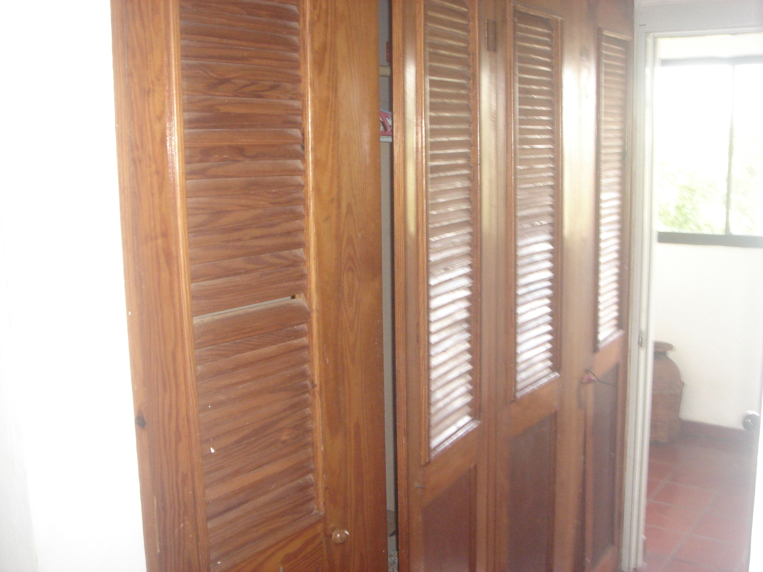Une porte en bois avec des lattes horizontales, donnant sur un espace extérieur.