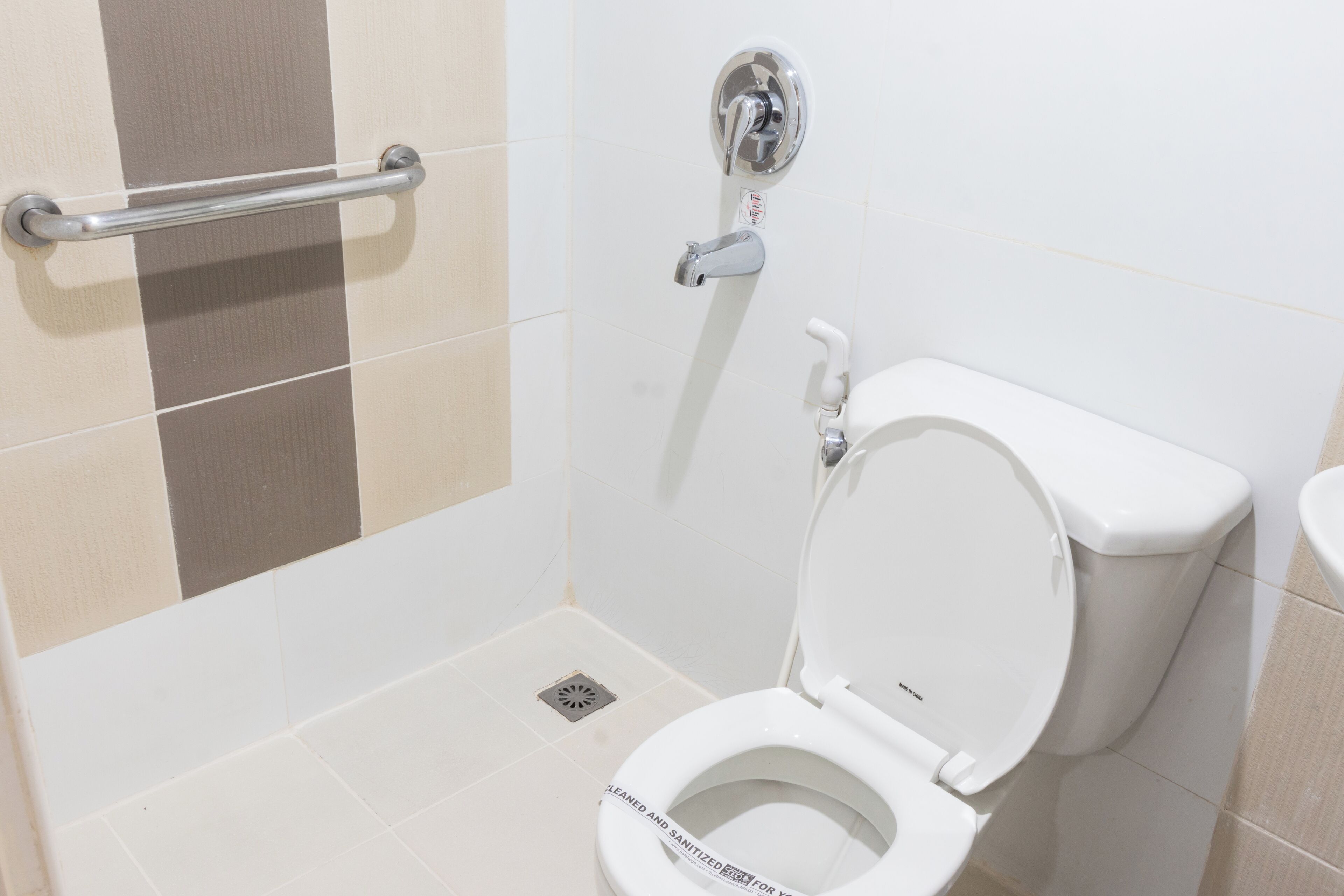 Een moderne badkamer met een wit toilet, een handgreep en een wandmengkraan.