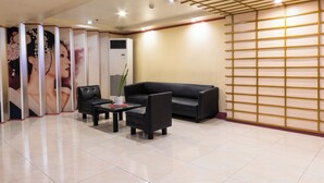 A reception area with a black leather sofa, a small table with a vase, and a decorative wall with a grid pattern. - Hotel Sogo Kalentong Marketplace (Mandaluyong)