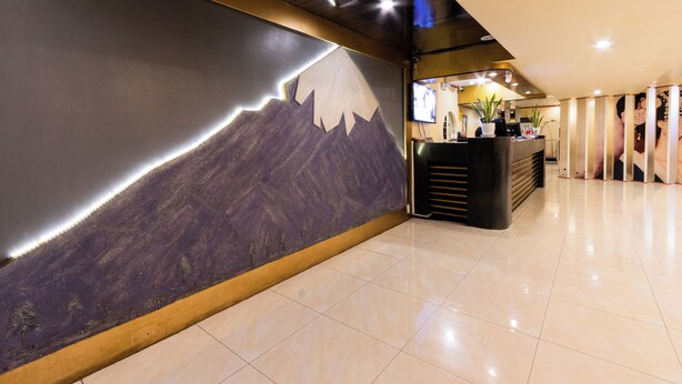 A hotel reception area with a mountain mural, a reception desk, and a modern interior design. - Hotel Sogo Kalentong Marketplace (Mandaluyong)