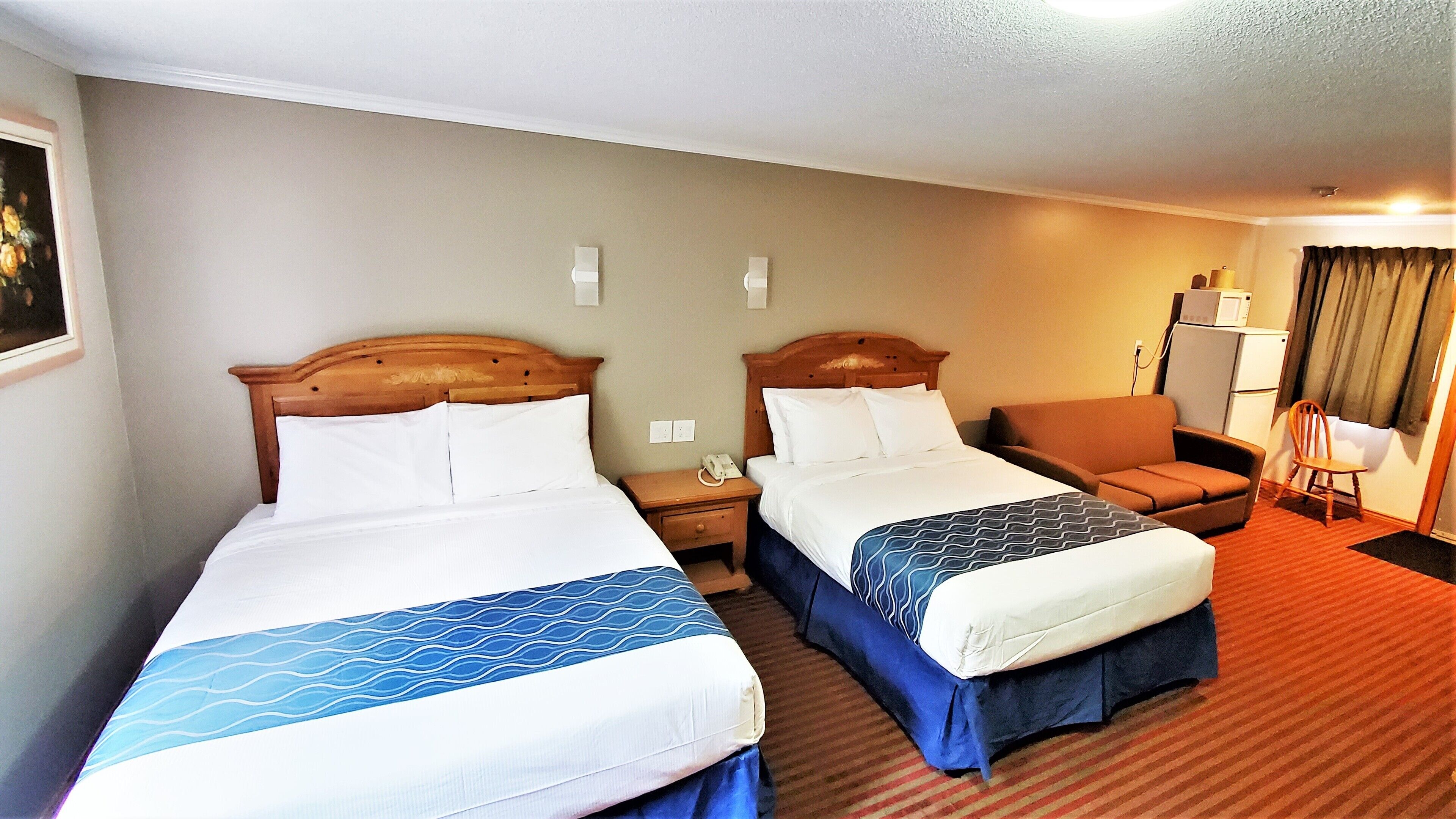 Une chambre d’hôtel avec deux lits, une chaise, un bureau et un four à micro-ondes.