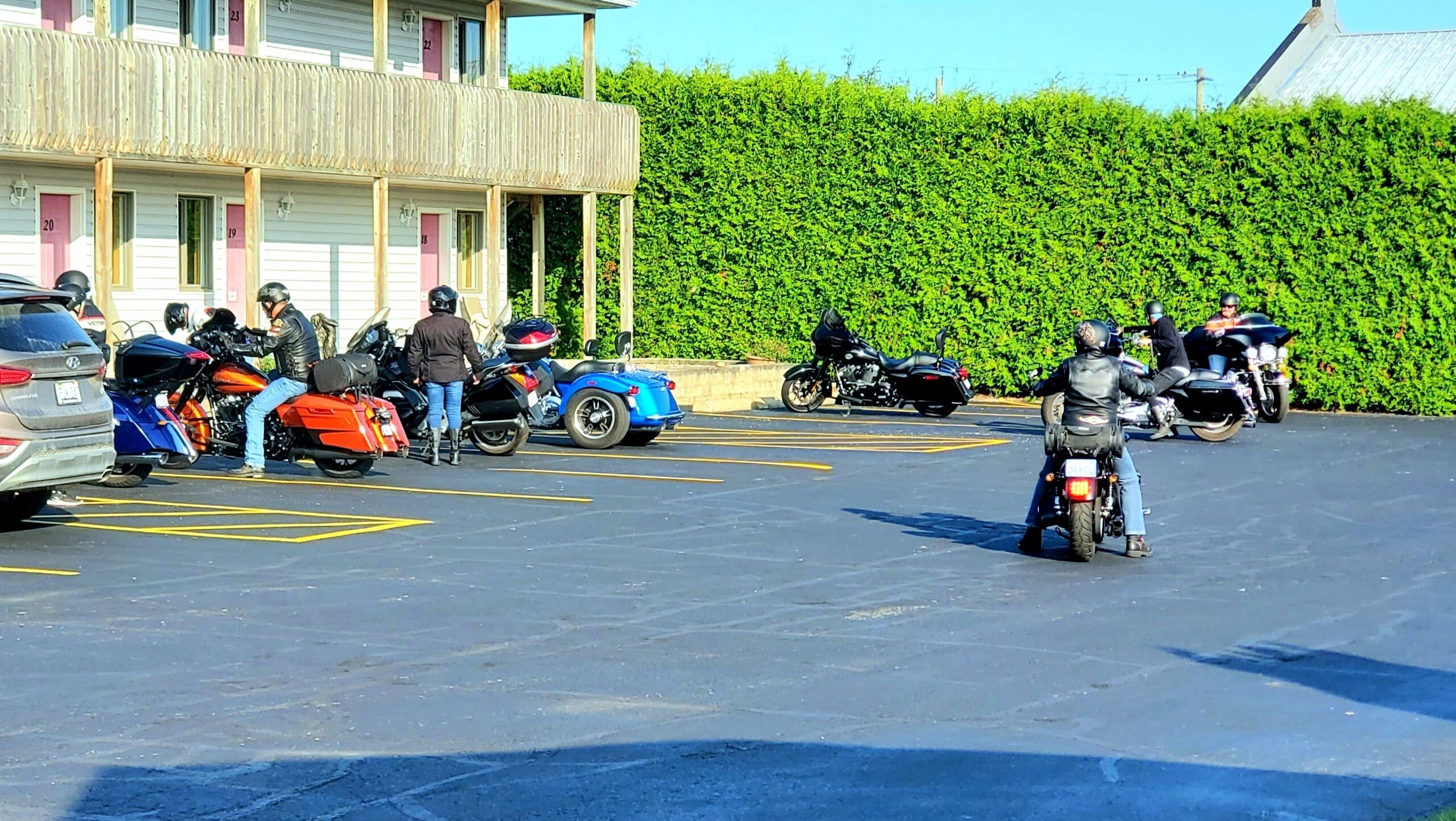 Uma área de estacionamento com várias motocicletas e um carro.