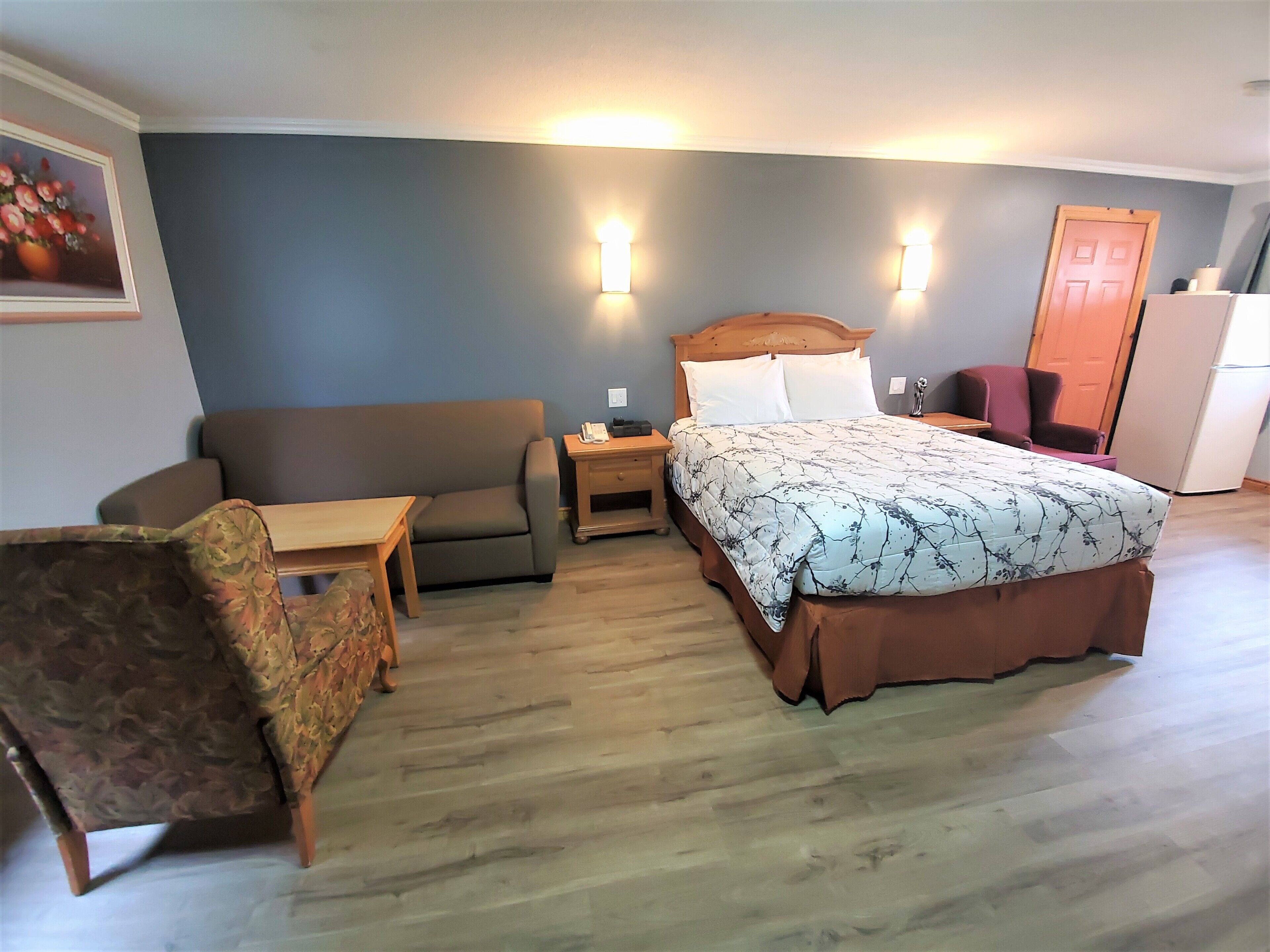 Quarto com cama, mesa de cabeceira, escrivaninha, cadeira, sofá e porta.