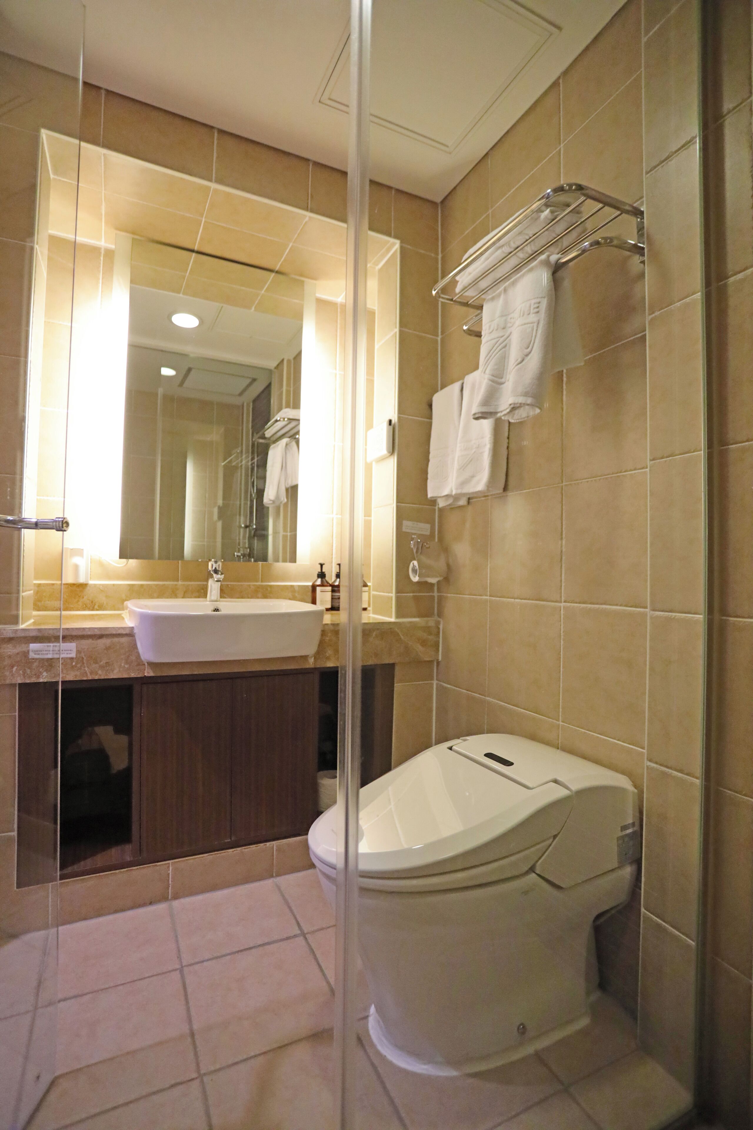 A modern bathroom with a large mirror, a sink, a toilet, and a glass shower enclosure.
