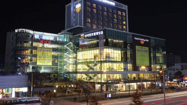 A multi-story hotel with a glass facade, signage for a wedding hall, and a bus stop in front. - Sunshine Hotel (Daejeon)