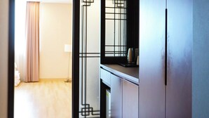 A hotel room with a sliding door leading to a balcony, a small kitchenette, and a carpeted floor. - Sunshine Hotel (Daejeon)