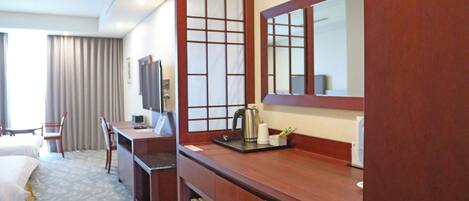 A hotel room with a bed, desk, chair, and a large mirror.