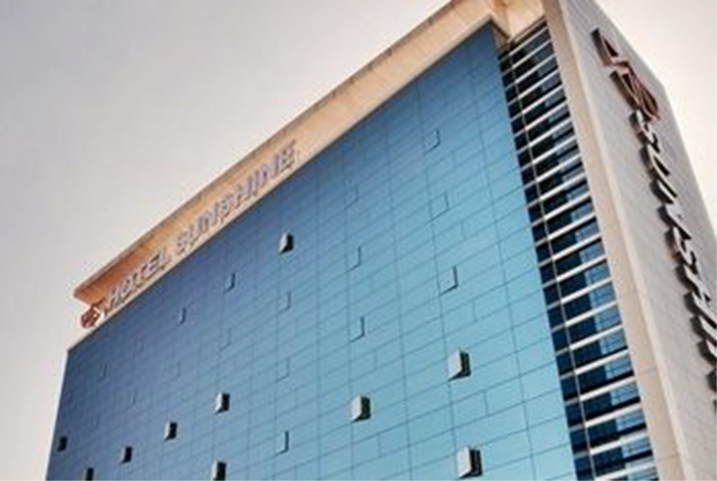 A modern hotel building with a prominent sign reading "HOTEL SUNSHINE."