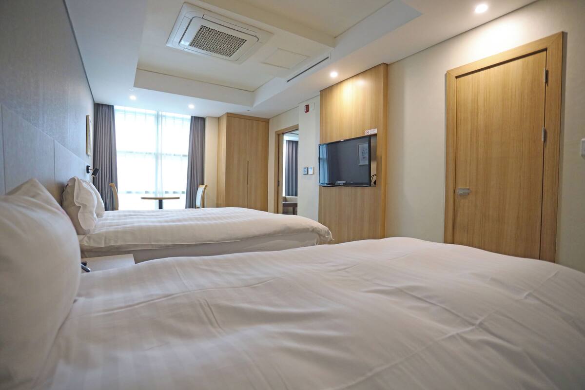 A hotel room with two beds, a television, and a wooden door.