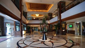 A spacious lobby with a central decorative fountain, multiple floors, and a modern design. - HARRIWAY GARDEN HOTEL CHANG AN (Dongguan)