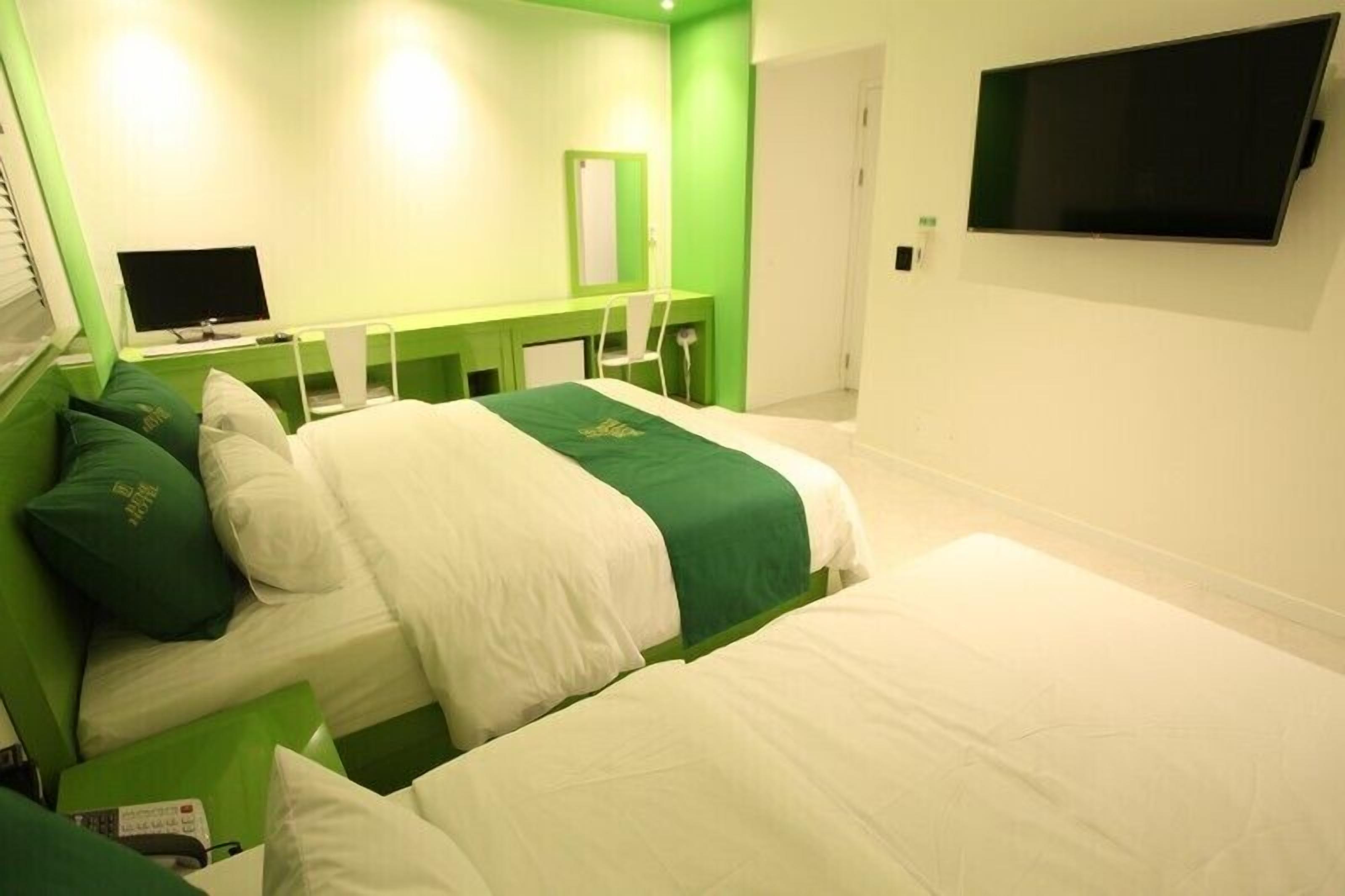 A hotel room with two beds, a desk, a chair, a television, and a mirror.